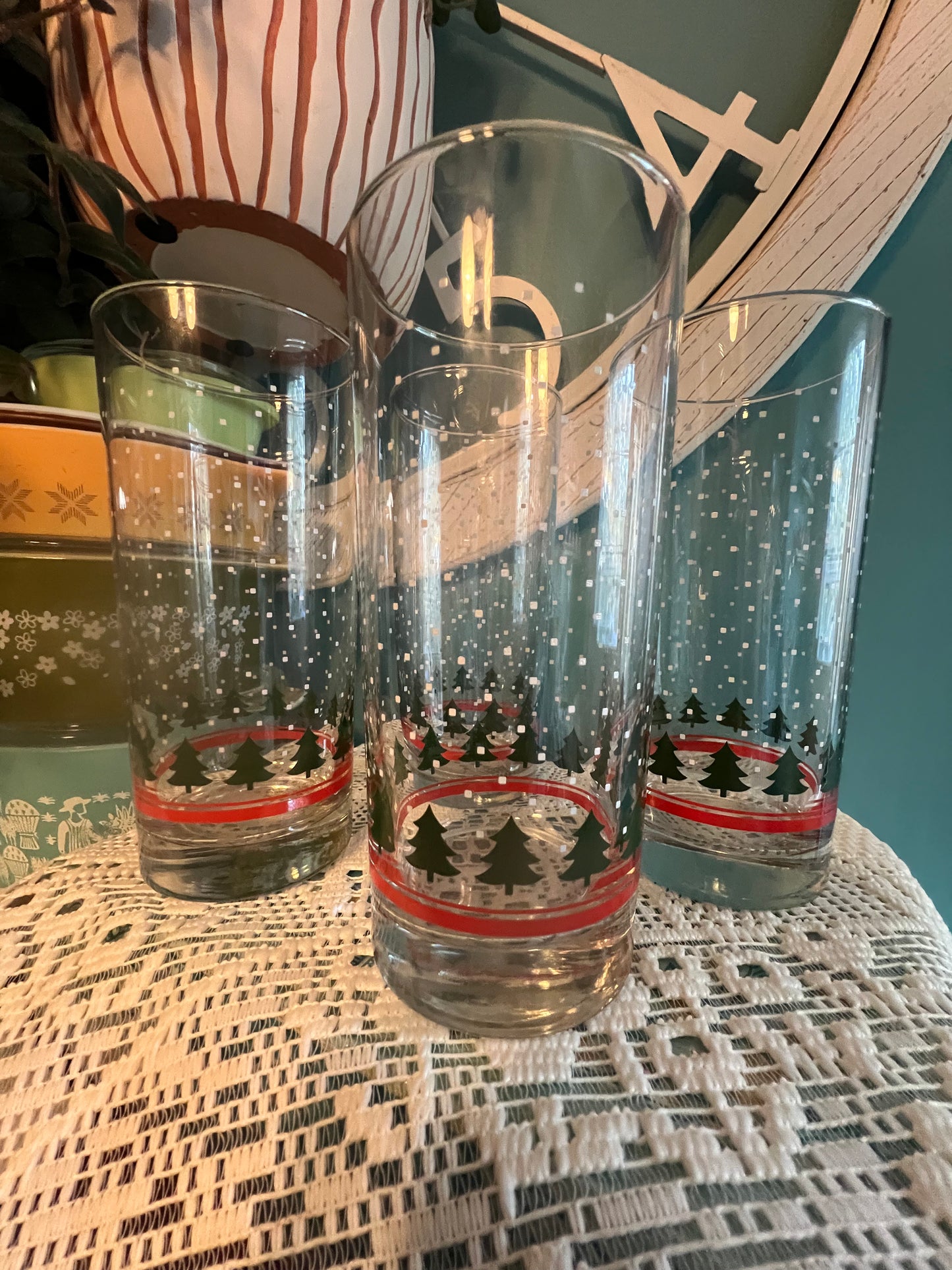Tall Libbey glassware with falling snow, pine tree, and red band design