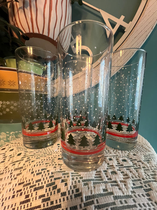 Tall Libbey glassware with falling snow, pine tree, and red band design